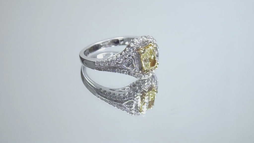 This is a video of a 1.35ct total weight natural fancy yellow not enhanced diamond ring with white diamond accents in white gold shown turning slowly on a mirrored background.