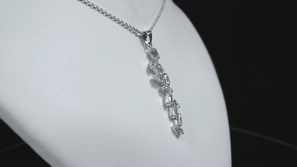This is a custom made .91ct natural baguette diamond necklace in 18K white gold rotating on a white neck in a video.