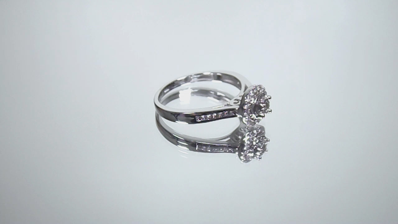 This is a video of a ladies' halo style small round diamond ring in white gold turning slowly on mirrored background.