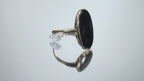 This is a vintage oval bezel set black onyx ring in 10K yellow gold.  It is 21mm long and 18mm wide on a mirrored surface rotating in a video.