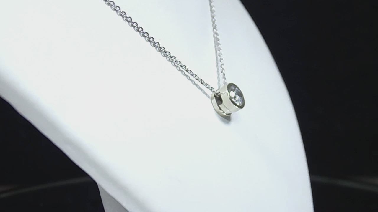 This is a bezel set slide .40ct natural diamond necklace in 14K white gold rotating on a white displace neck in a video.