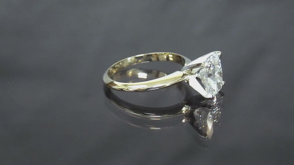 This is a 2.01ct natural elongated cushion cut diamond solitaire in yellow gold shown turning slowly on a grayish mirrored background.