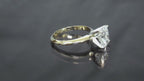 This is a 2.01ct natural elongated cushion cut diamond solitaire in yellow gold shown turning slowly on a grayish mirrored background.