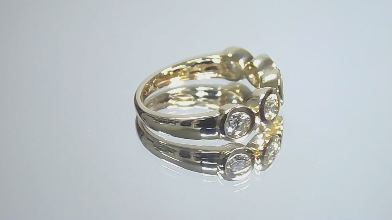 This is a video of a bezel set 5-stone natural 1ct total weight diamond band in yellow gold turning slowly on a mirrored background.