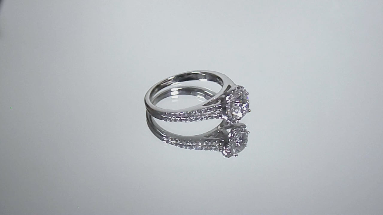 This is a video of a halo style natural round diamond ring in white gold turning slowly on a mirrored background.