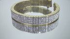 This is a 22.00ct natural princess cut diamond bracelet with 76.4 grams of 18K yellow gold on a mirrored surface rotating in a video.