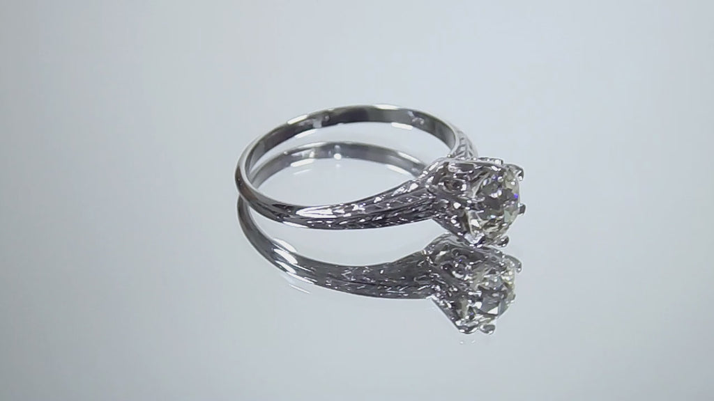 This a video of an antique women's solitaire ring from the 1880's with a natural old mine cut center shown turning slowly on a mirrored background.
