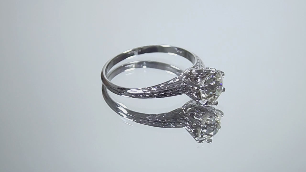 This a video of an antique women's solitaire ring from the 1880's with a natural old mine cut center shown turning slowly on a mirrored background.