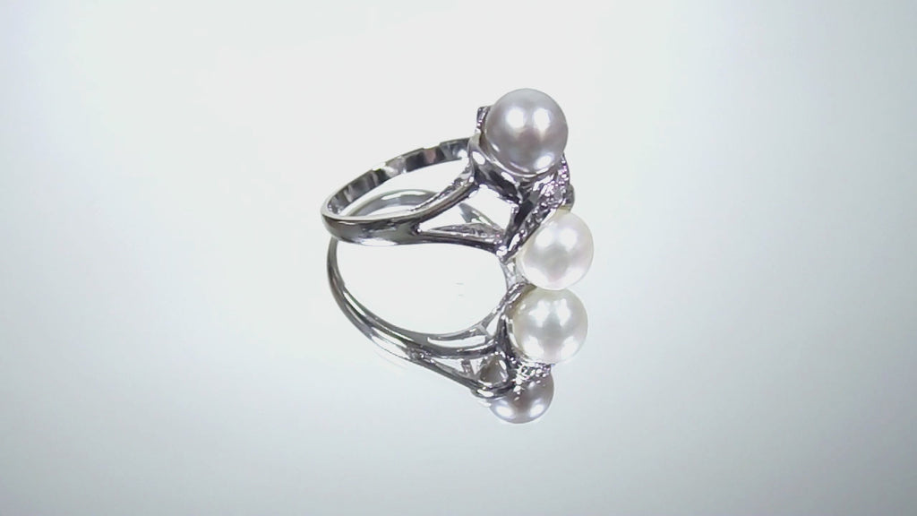 This is a video of a fully restored like new 2-pearl ring - one gray and one white pearl with diamond accents shown turning slowly on a mirrored background.