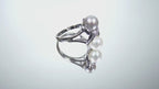 This is a video of a fully restored like new 2-pearl ring - one gray and one white pearl with diamond accents shown turning slowly on a mirrored background.