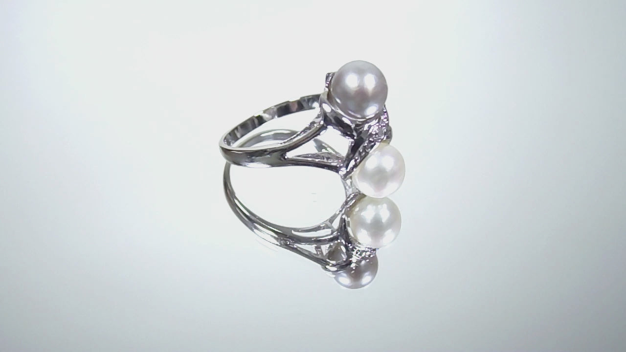 This is a video of a fully restored like new 2-pearl ring - one gray and one white pearl with diamond accents shown turning slowly on a mirrored background.