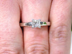 Diamond ring on a woman's finger with a close-up view it's a princess cut diamond solitaire ring in white gold.