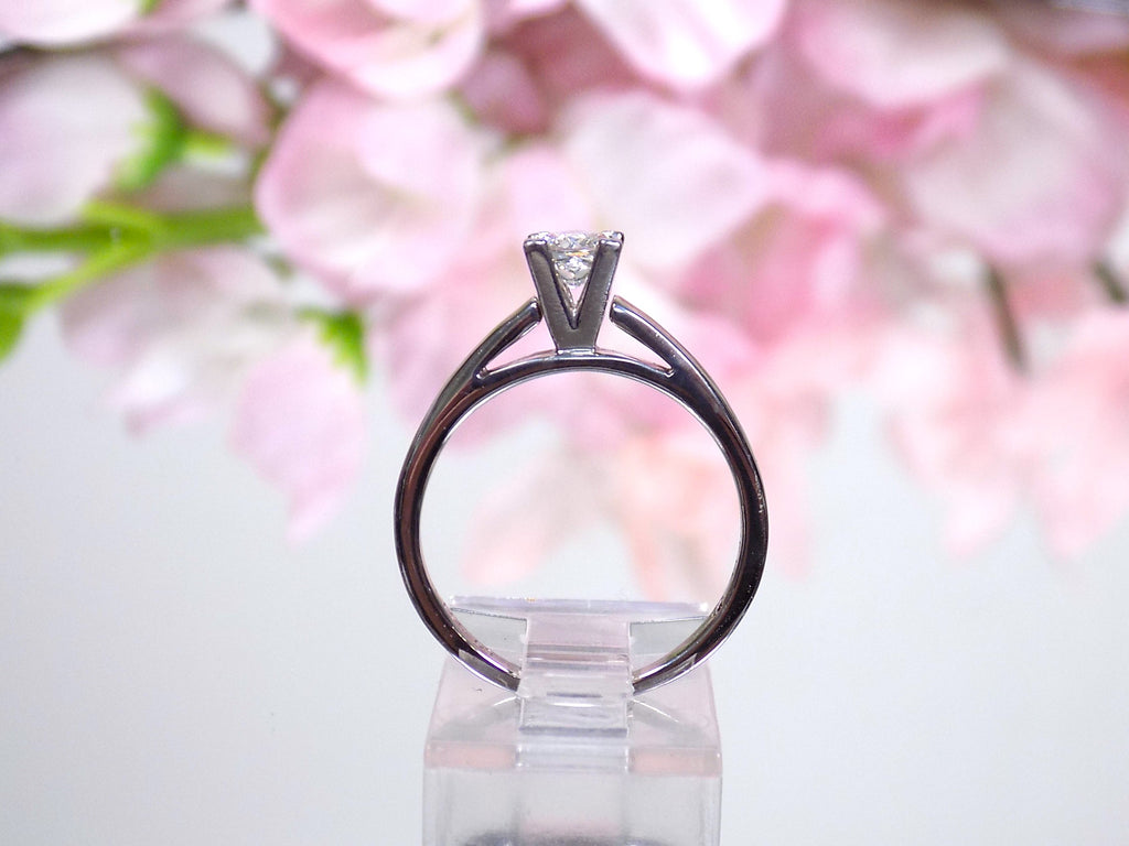This is side view of a natural diamond princess cut solitaire engagement ring in white gold with floral background. 