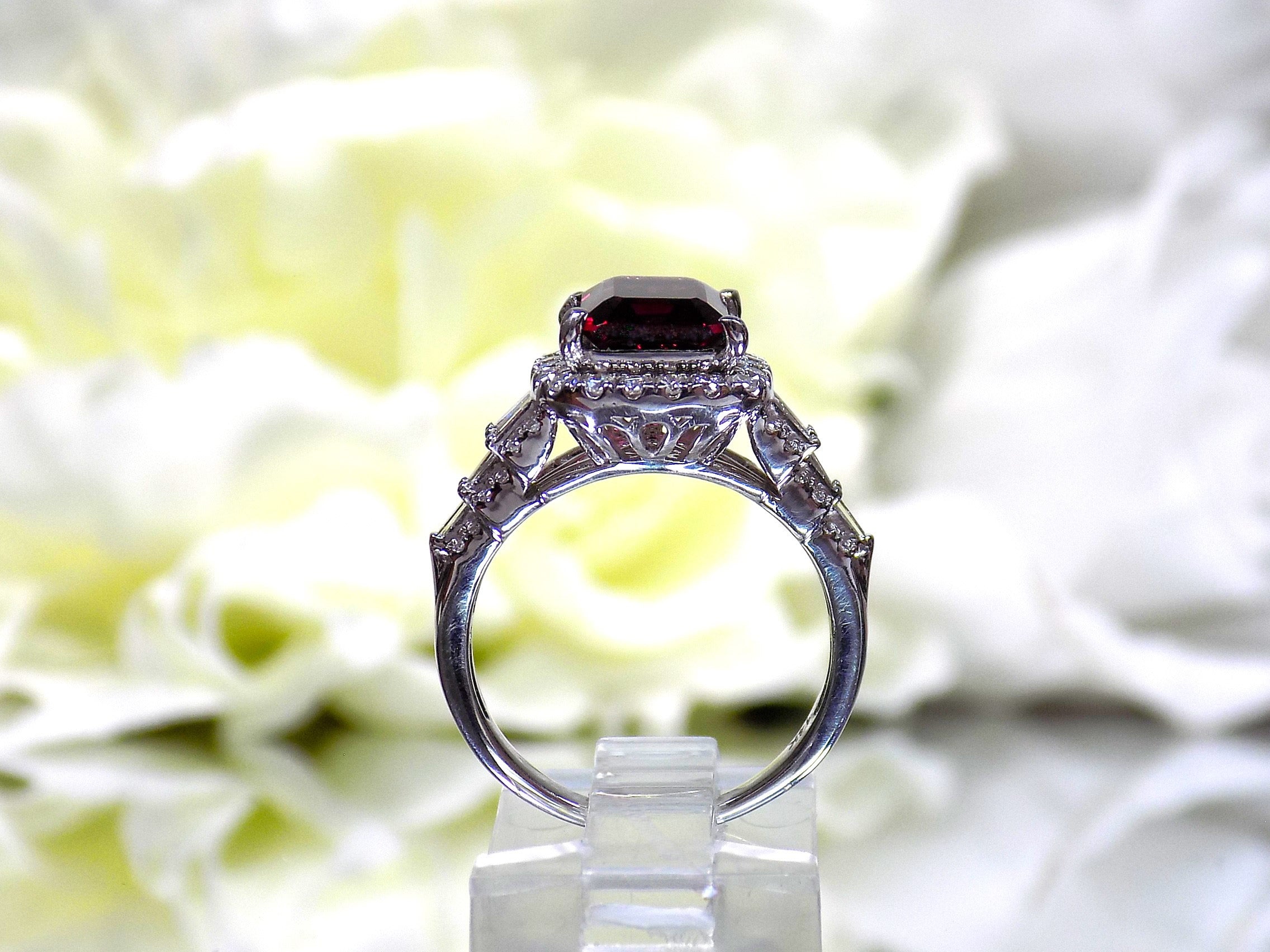This is a side view of a woman's 3.95ct total weight rhodolite garnet and diamond ring in white gold with yellow white background.