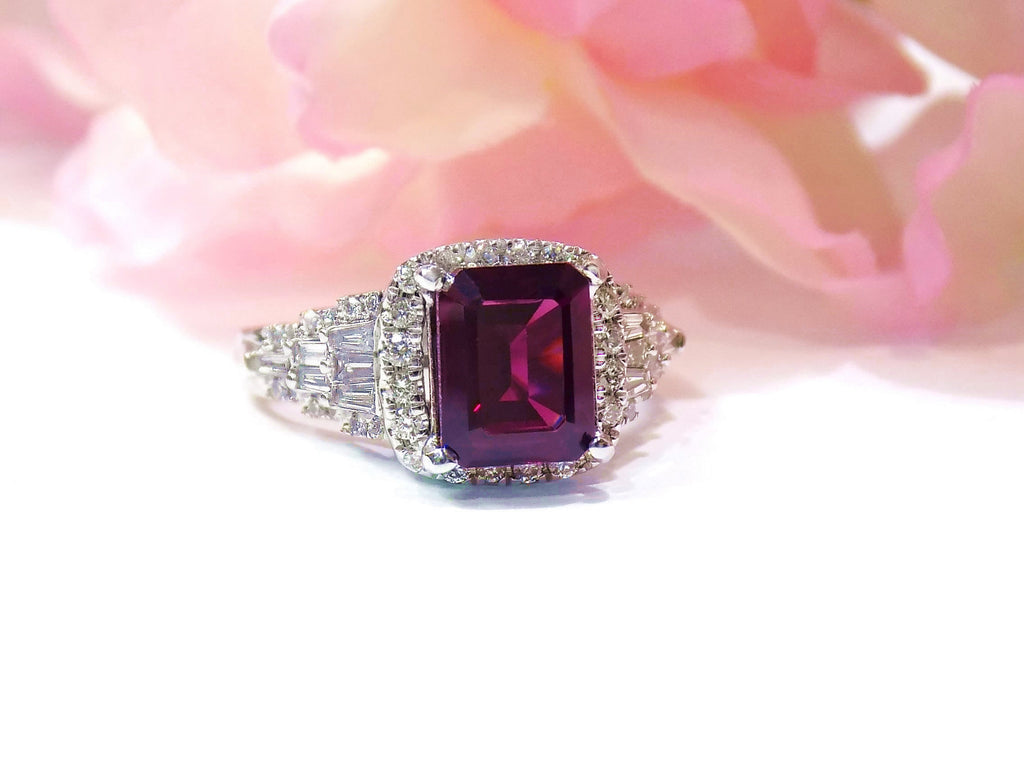 This is a woman's 3.95ct total weight rhodolite garnet and diamond ring in white gold with pink rose background.