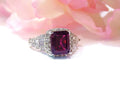 This is a woman's 3.95ct total weight rhodolite garnet and diamond ring in white gold with pink rose background.