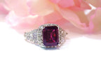 This is a woman's 3.95ct total weight rhodolite garnet and diamond ring in white gold with pink rose background.
