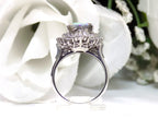This is a women's ring with 2.51ct lightning ridge natural opal surrounded by .72ct natural baguette and round diamonds in 14K white gold with a white floral background from a side view.