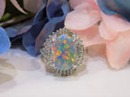 This is a women's ring with 2.51ct lightning ridge natural opal surrounded by .72ct natural baguette and round diamonds in 14K white gold with a blue and pink floral background.