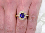 This is a women's natural 1.47ct oval sapphire ring with .33ct total weight natural diamond accents in 14K yellow gold on a women's finger.