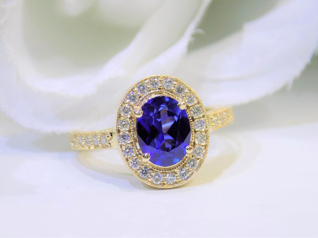 This is a women's natural 1.47ct oval sapphire ring with .33ct total weight natural diamond accents in 14K yellow gold on a white background.