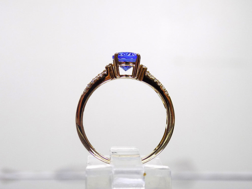 This is a women's natural 1.35ct natural oval tanzanite ring with .36ct natural round diamond accents in 14K yellow gold on a white background from a side view.