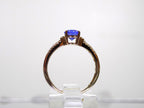 This is a women's natural 1.35ct natural oval tanzanite ring with .36ct natural round diamond accents in 14K yellow gold on a white background from a side view.