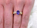 This is a women's natural 1.35ct natural oval tanzanite ring with .36ct natural round diamond accents in 14K yellow gold on a women's finger.
