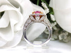 This is a women's ring with a natural 2.21ct pink sapphire in the center with a total weight of .86ct natural round diamond accents set in 18K white and yellow gold with a white floral background in a side view.