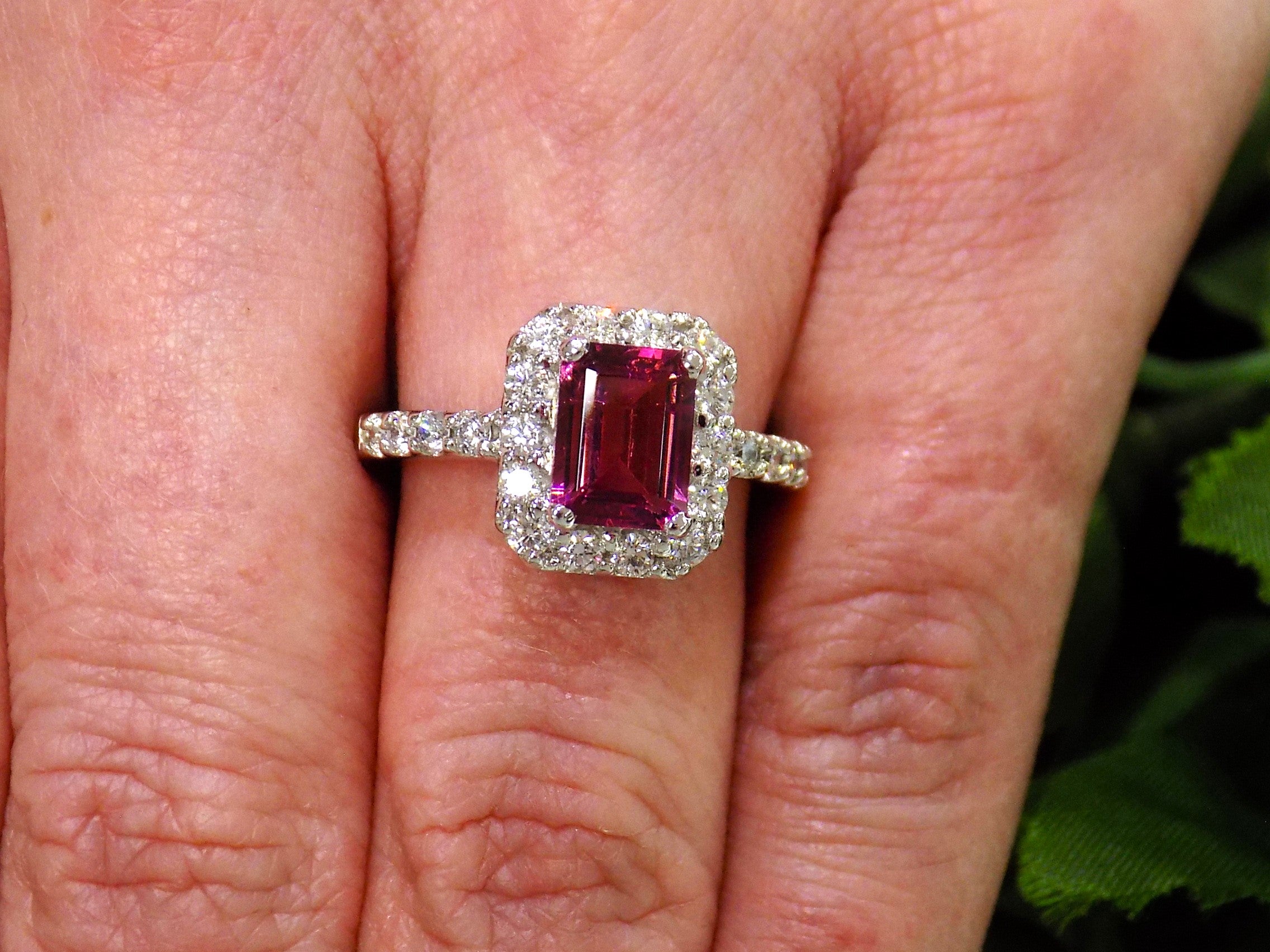 This is a women's ring with a 1.47ct natural emerald cut pink tourmaline surrounded by .67ct natural round diamonds set in 14K white gold on a women's finger.