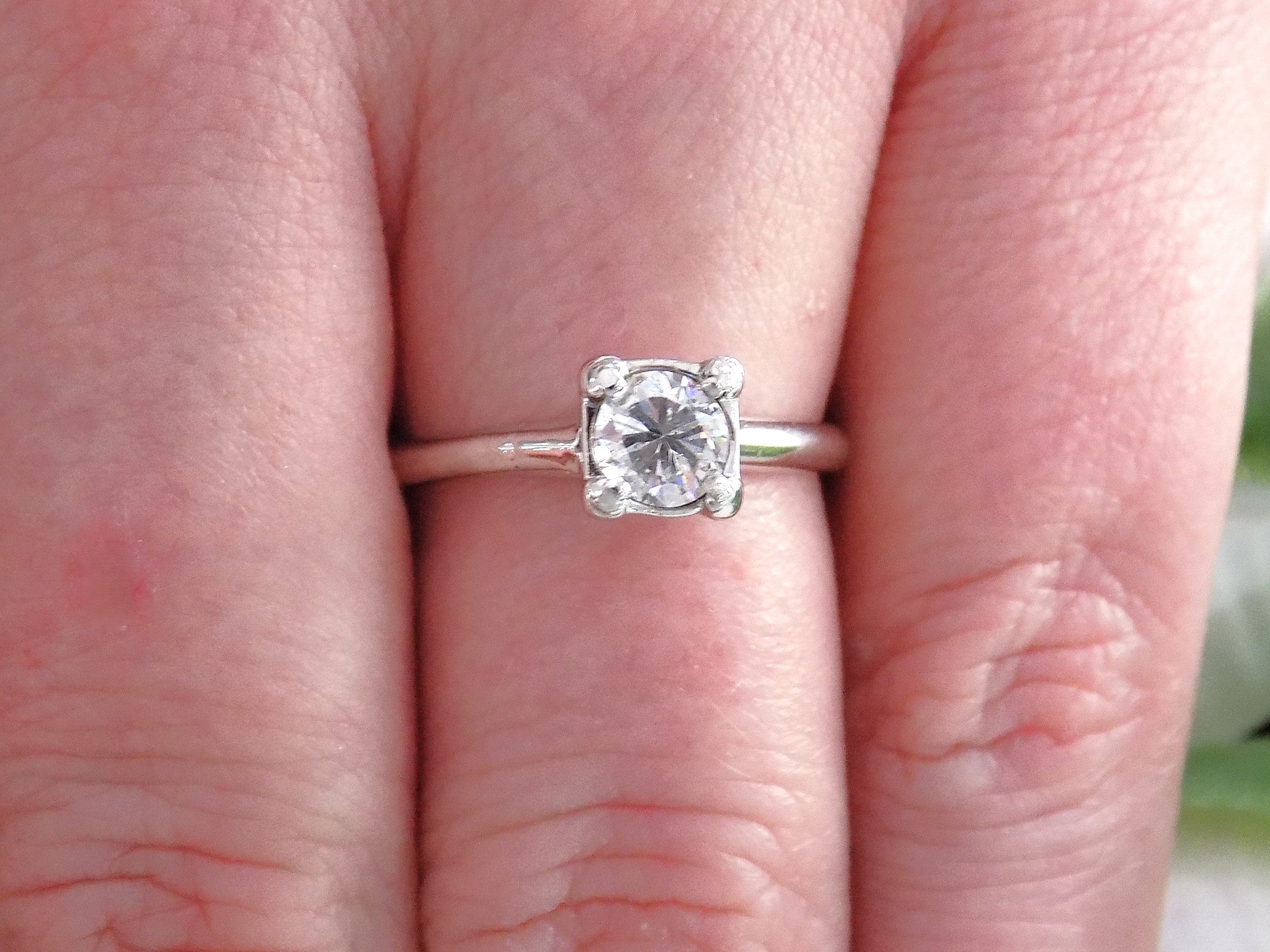This is an estate .45ct round diamond solitaire ring in white gold shown on a woman's finger.
