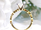 This is a side view of a women's natural round brilliant diamond ring with a 1.10ct round center and .22ct in diamond accents set in yellow gold shown with a white background.