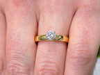 This is .45ct natural round brilliant solitaire ring on wider yellow gold band shown on a woman's finger.