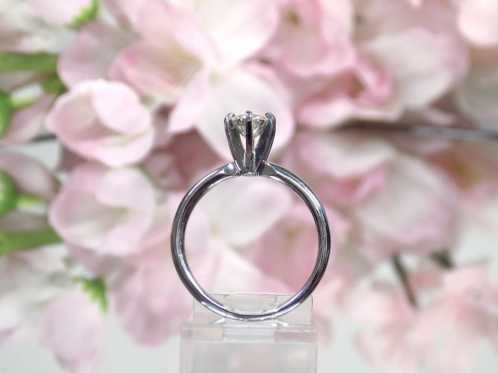 The is a side view of natural .60ct round brilliant diamond solitaire engagement ring in white gold with flowery background.
