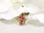 This is a women's .50ct total weight ruby and diamond cluster ring set in 14K yellow gold on a white floral background.