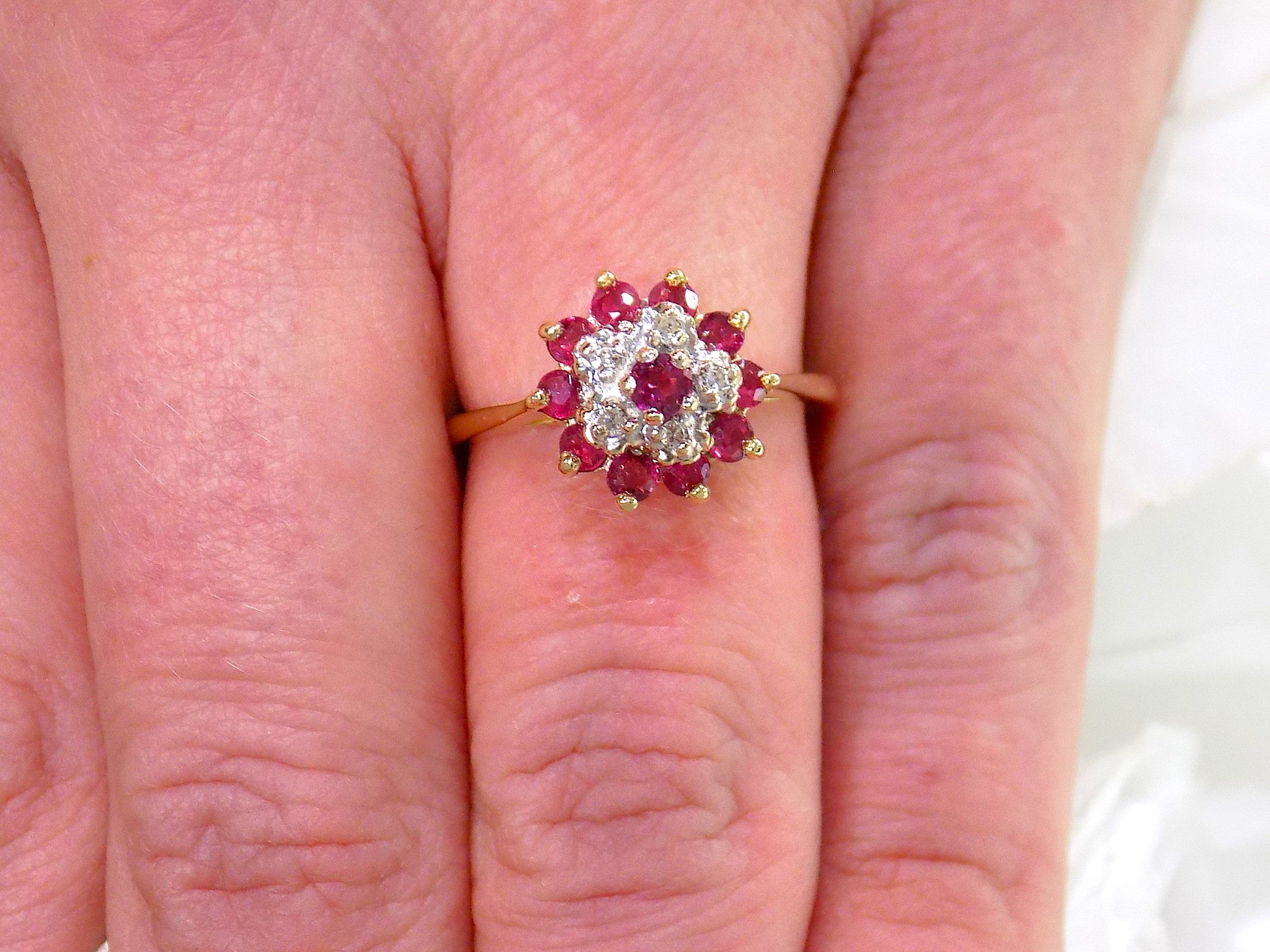 The is a genuine ruby and diamond ring in  yellow gold from our estate collection in like new condition shown on a woman's finger.