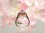 The is side view of a genuine ruby and diamond ring in  yellow gold from our estate collection in like new condition with pink  flowery background.
