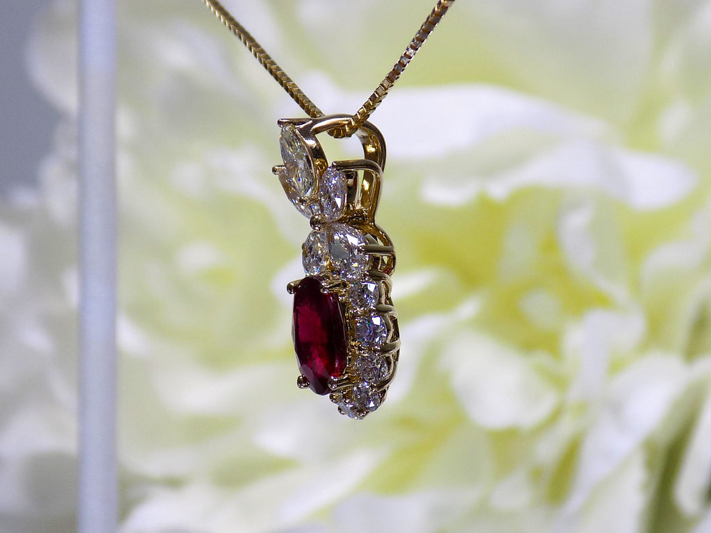 This is a side view of a woman's 3.06ct total weight oval ruby plus natural diamond pendant is in yellow gold with yellow/white flowery background.
