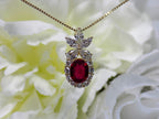 This is a woman's 3.06ct total weight oval ruby plus natural diamond pendant is in yellow gold with yellow/white flowery background.