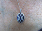 This is a women's 2.35ct total weight natural sapphire and diamond pendant in white gold shown on a woman's neck.