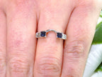 This is a white gold sapphire and diamond ring guard or wrap shown on a ladies' finger without the solitaire placed in the middle.