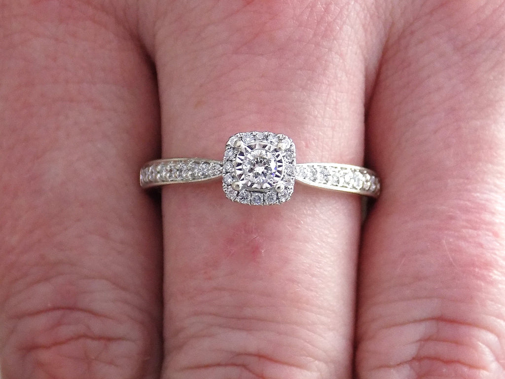 Preowned small natural diamond ring on a woman's finger in the halo design great for promise ring or inexpensive engagement ring.