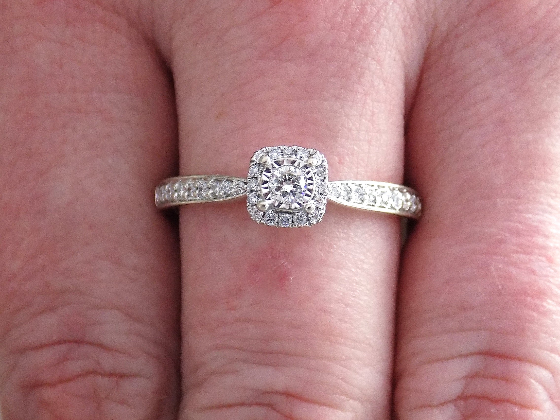 Preowned small natural diamond ring on a woman's finger in the halo design great for promise ring or inexpensive engagement ring.