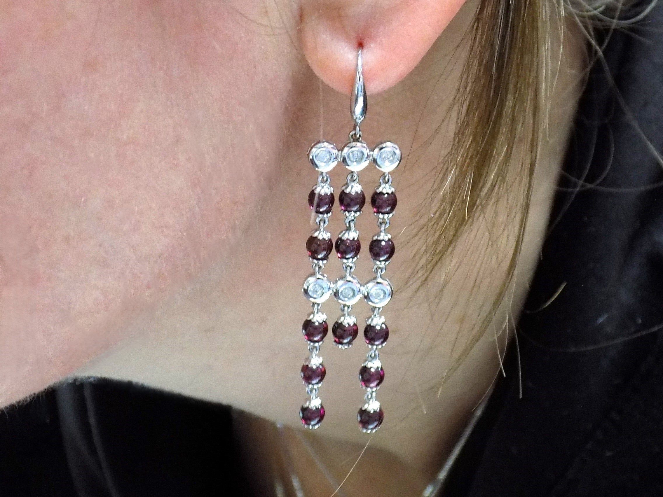 These are custom made genuine red tourmaline and natural diamond drop earrings in 18K white gold from our estate collection shown in woman's ear.