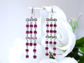These are custom made genuine red tourmaline and natural diamond drop earrings in 18K white gold from our estate collection shown with white flower background.
