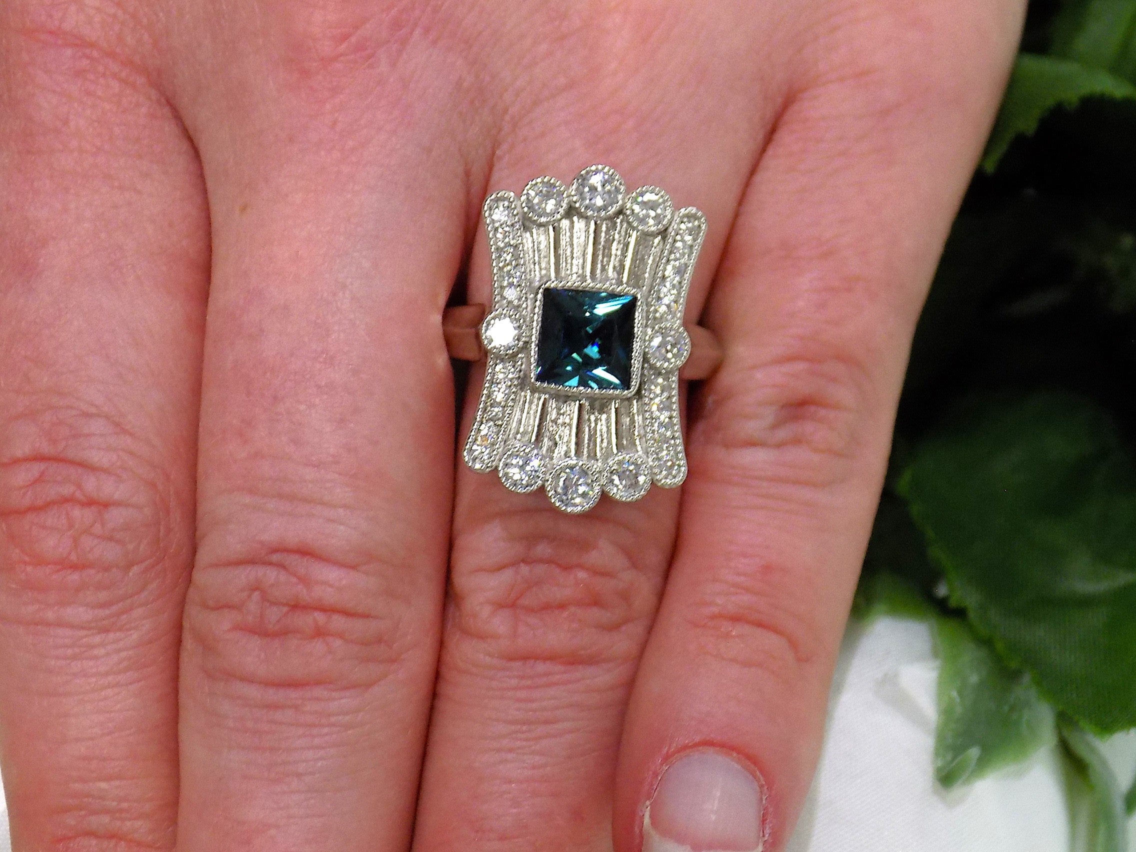 This is a women's 1.78ct total weight natural indicolite tourmaline and diamond Victorian style ring in white gold shown on a woman's finger.