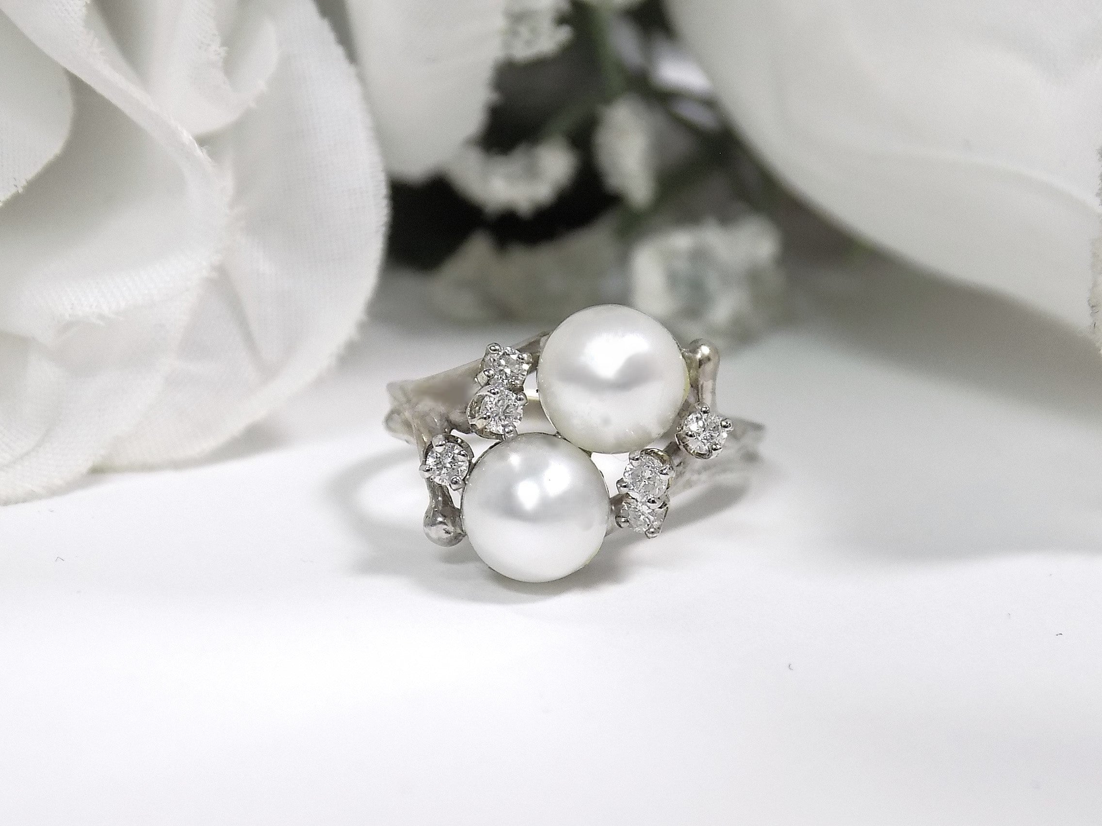 This is a twin cultured pearl ring with natural diamond accents in white gold shown on a white background.