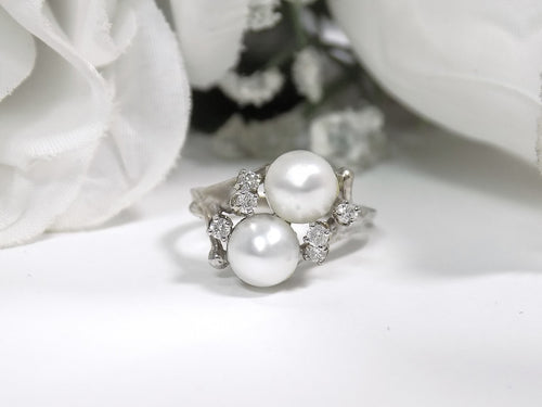 This is a twin cultured pearl ring with natural diamond accents in white gold shown on a white background.