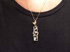 This is a .12ct total weight natural diamond  leaf style looking pendant in two tone 10K white and yellow gold on a ladies neck with a black shirt.