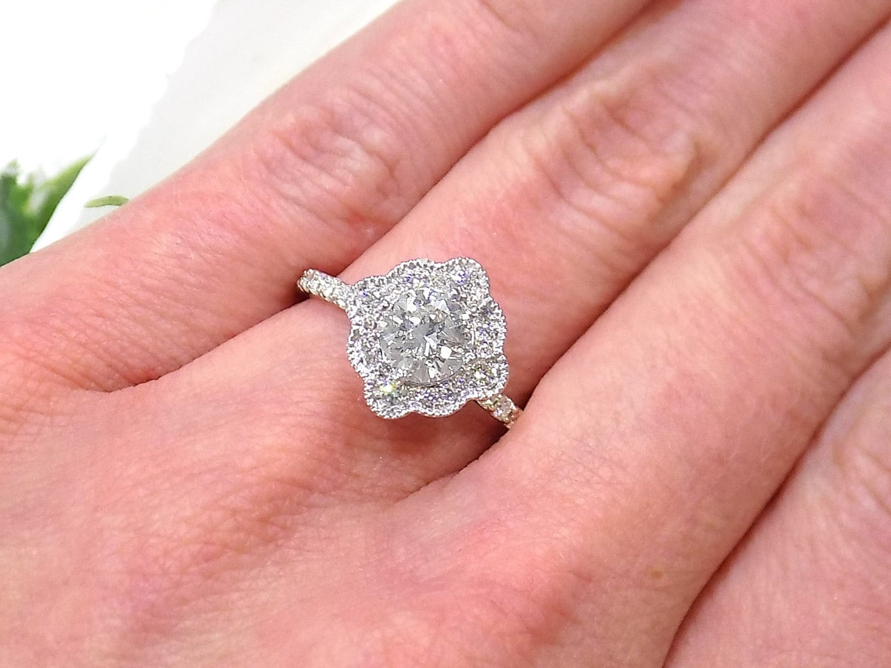 This is a 1.25ct total weight natural diamond ring with a .84ct natural round brilliant diamond in the center in white gold shown on a woman's finger.